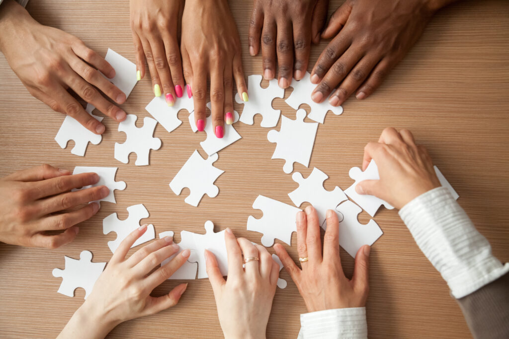 Hands of diverse people assembling a jigsaw puzzle